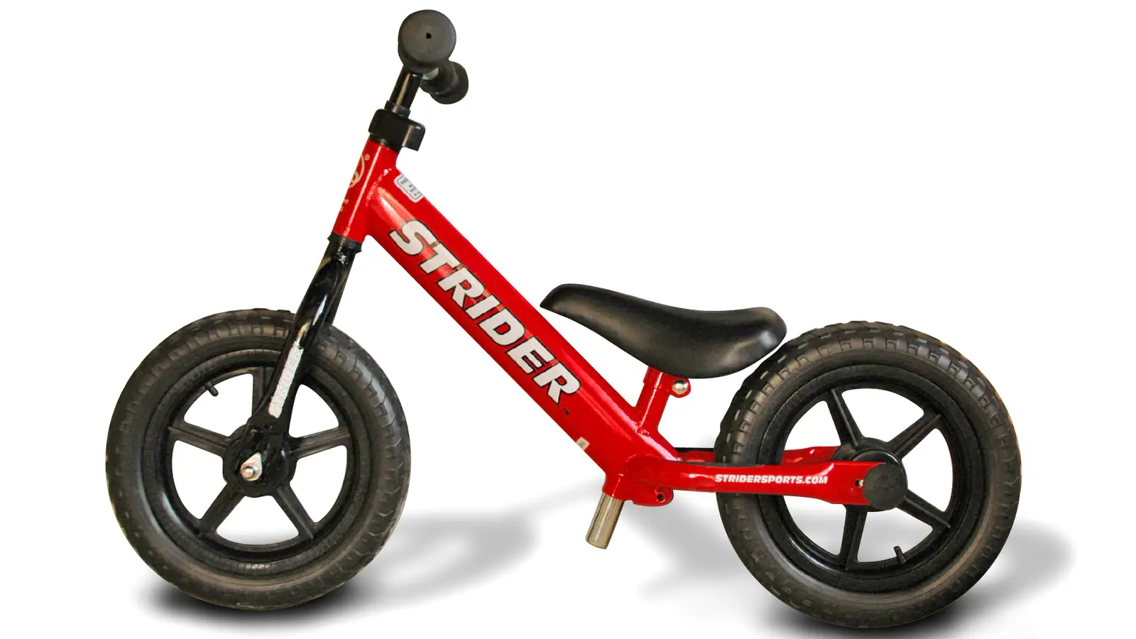 Red Strider balance bike photographed from the side on a white background