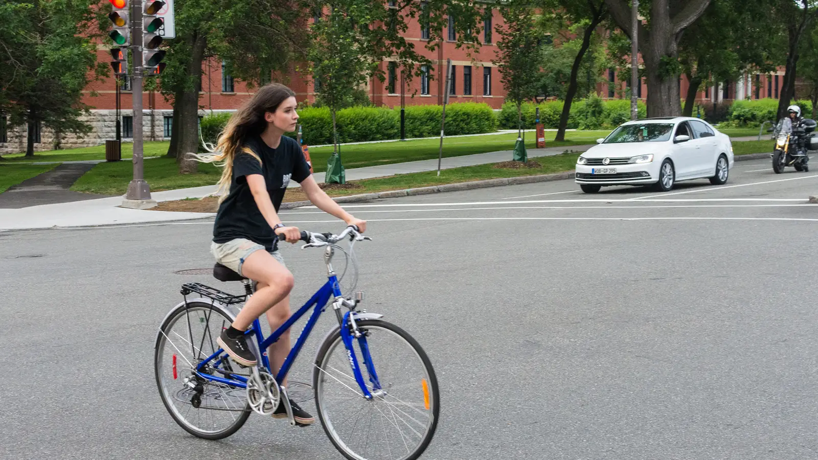 Woman riding a blue step-through city bike across a street