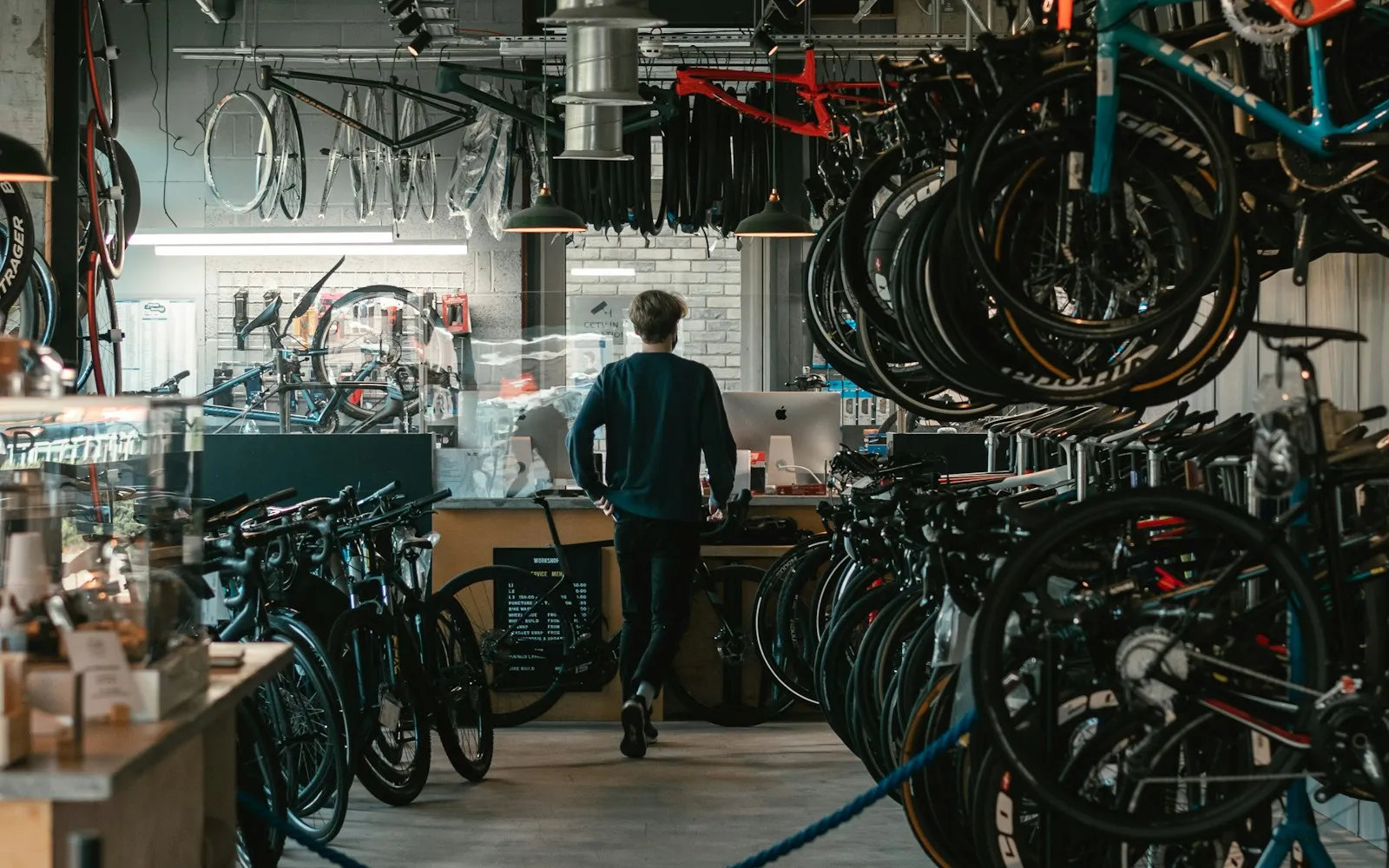 Bike shop with many frame sizes hanging and parked while a customer stands at the counter