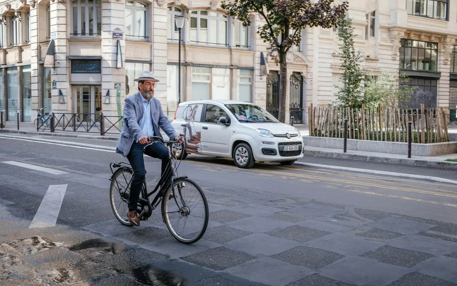 Rider commuting upright on a city bike across a Paris street
