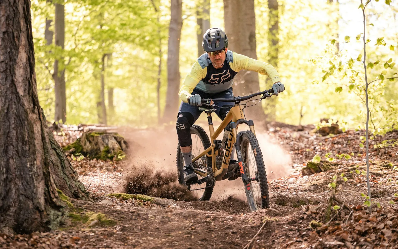 Mountain biker on a full-suspension trail bike riding a forest dirt trail