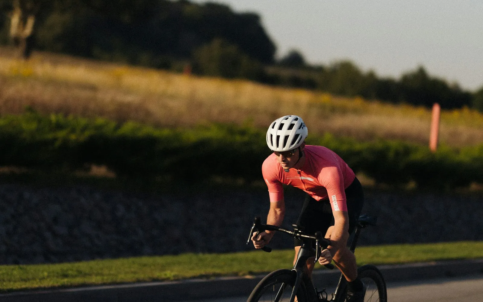 Cyclist in a road jersey riding a drop-bar road bike on pavement